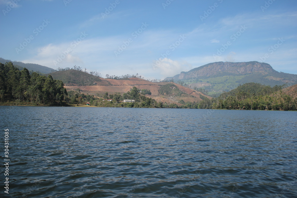 Beautiful landscape of blue-sky with a white clouds and a dry grass fields. Boating in the Ooty Lake, Reflection of blue sky and beautiful clouds in lake Ooty - Tamil Nadu