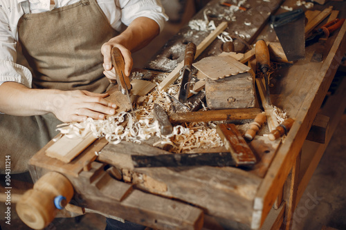 Man working with a wood. Carpenter in a white shirt