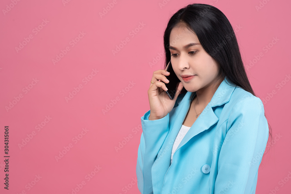 Portrait of asian business woman using mobile phone on pink background in studio. Woman holding smartphone. Portrait of asian business woman using mobile phone on pink background in studio. Woman holding smartphone.