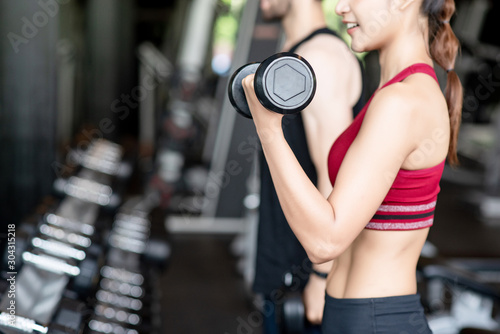 Close up hand of young healthy woman lighting dumbbells in the gym.