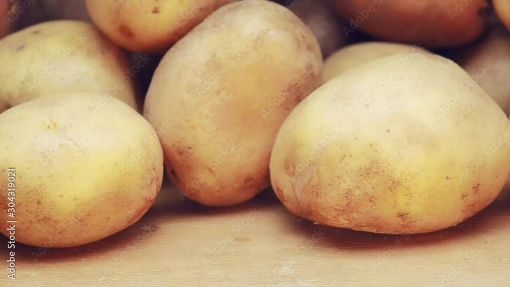 Panning shot alongside organic potato on wooden background. Dolly camera move, slowly sliding shot along potatoes is lying in bulk. Rustic vegetables from farmhouse field Panning shot alongside organic potato on wooden background. Dolly camera move, slowly sliding shot along potatoes is lying in bulk. Rustic vegetables from farmhouse field