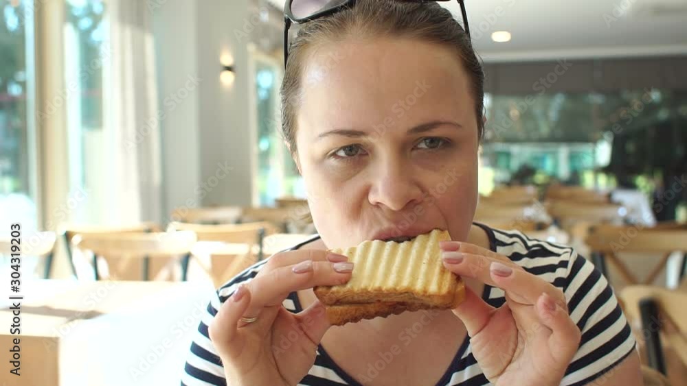 A young woman is having Breakfast in the hotel restaurant, she is eating grilled toast. Slow motion. A young woman is having Breakfast in the hotel restaurant, she is eating grilled toast. Slow motion.