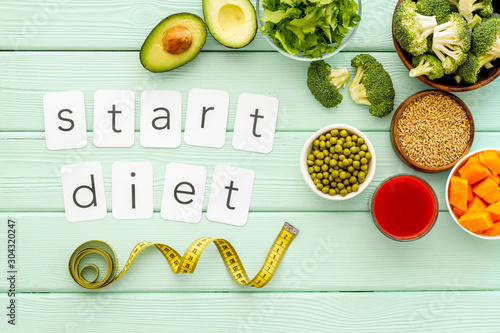 Start diet text near healthy food on green wooden background top view