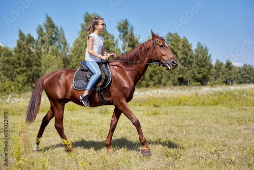 Teenager girl riding a brown horse, horseback riding for people in the park