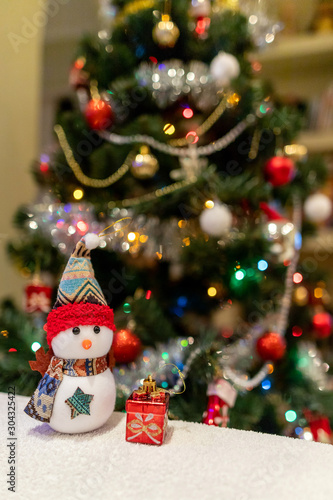 snowman with a gift under the Christmas tree