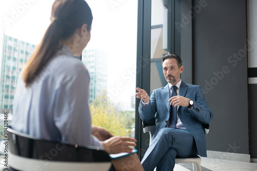 Businessman wearing elegant suit speaking with famous journalist photo