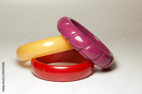 Close up view of vintage bakelite bangle bracelets in varying colors and widths on white background photo
