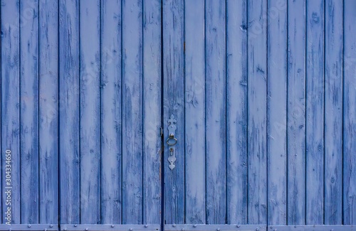 A rustic old barn door, painted lavender blue, in Provence, France.