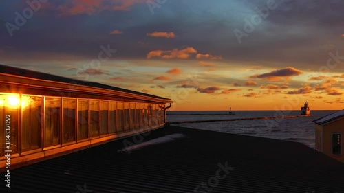 Moving drone aerial view of dramatic sunrise, reflection in windows, with bright but lonely Lighthouse beacon. photo