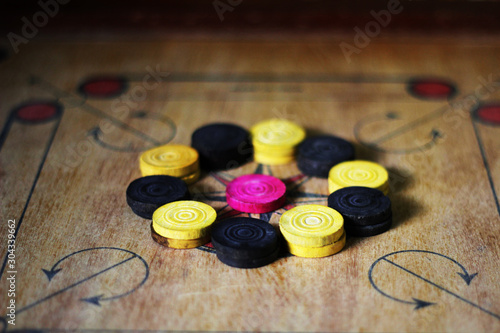 A game of carom set and ready to play.A game of carrom with pieces carrom man on the board carrom.Carom board game, selective focus.