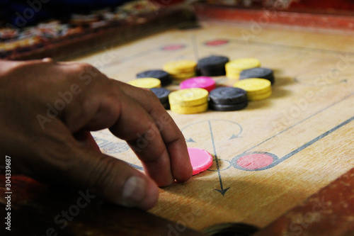 A game of carrom with pieces carrom man on the board carrom.Carom board game, selective focus.