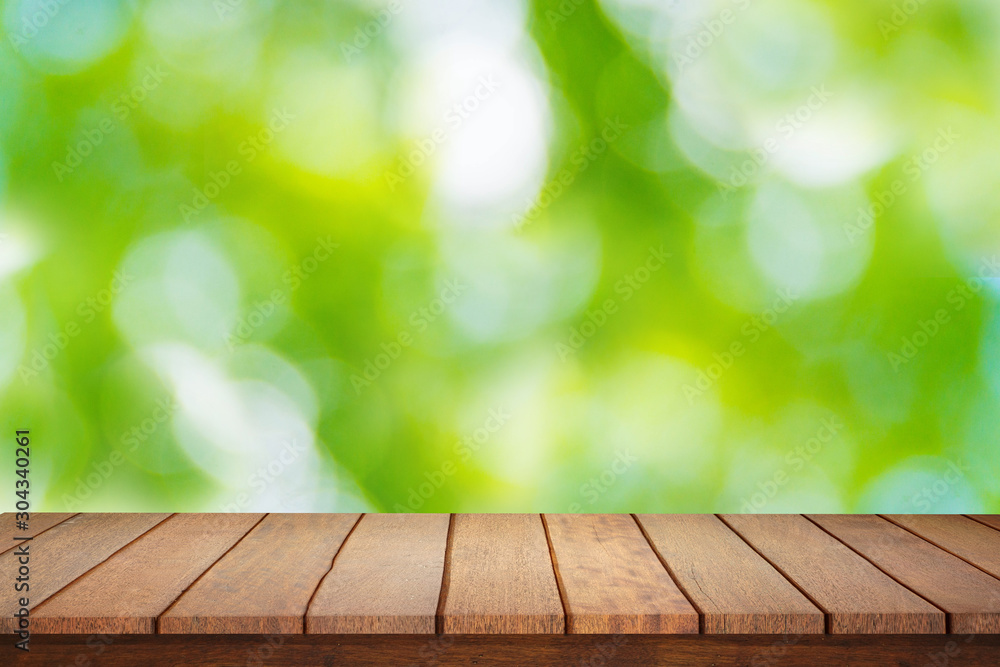 Empty plank brown wood table top with blur green tree texture background.