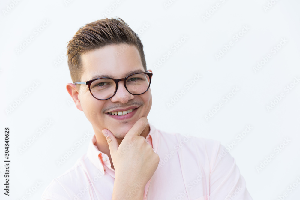 Closeup of joyful guy in eyewear touching chin, looking at camera and smiling. Young man in glasses standing isolated over white background. Male close-up portrait concept Closeup of joyful guy in eyewear touching chin, looking at camera and smiling. Young man in glasses standing isolated over white background. Male close-up portrait concept