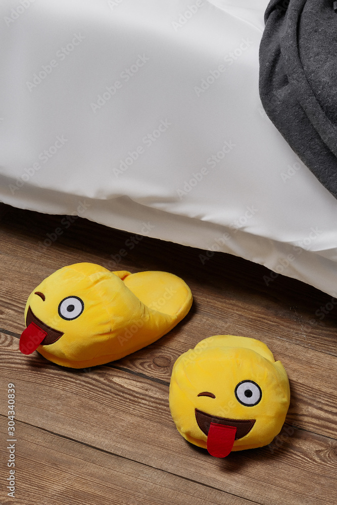 shot yellow plush house slippers made as the winking emoji with out tongue.