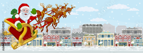 Christmas street scene with Santa Claus in his Christmas sleigh with reindeer flying over Victorian style houses, shops and other buildings in the snow.