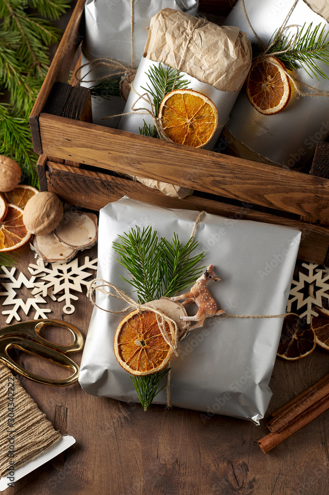 Packaging christmas present handmade gift boxes decorated with silver paper with dried orange slices