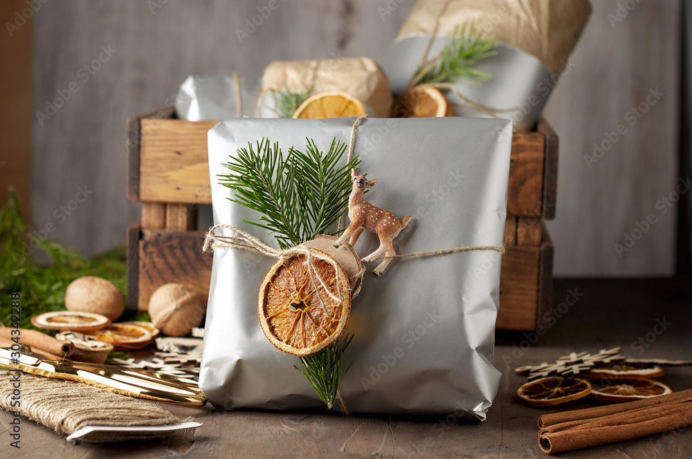 Packaging christmas present handmade gift boxes decorated with silver paper with dried orange slices