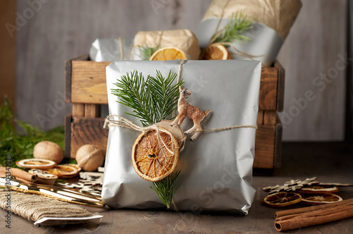Obraz na płótnie Packaging christmas present handmade gift boxes decorated with silver paper with dried orange slices w salonie