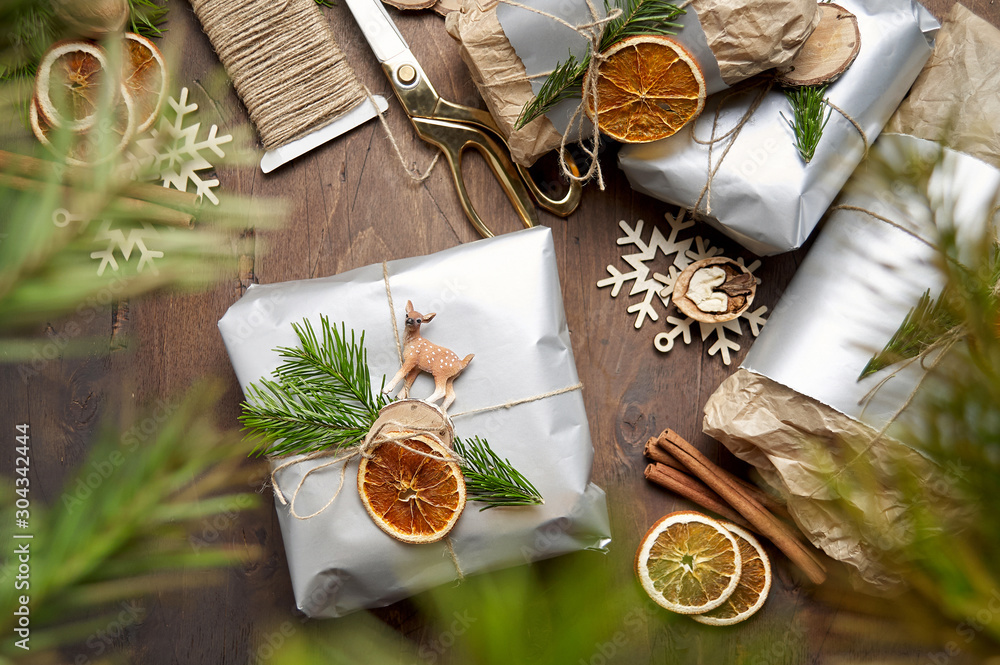 Packaging christmas present handmade gift boxes decorated with silver paper with dried orange slices