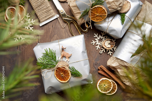 Obraz na płótnie Packaging christmas present handmade gift boxes decorated with silver paper with dried orange slices w salonie