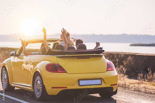 The four friends travel in a yellow cabriolet