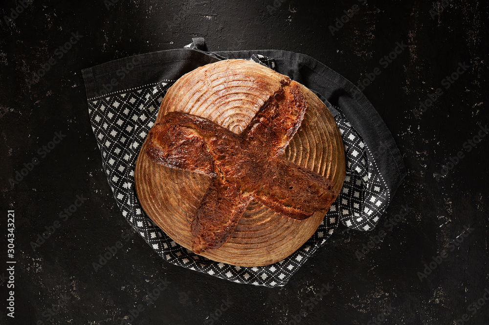 Freshly baked Artisan sourdough bread loaves with kitchen towel on black concrete backgroun