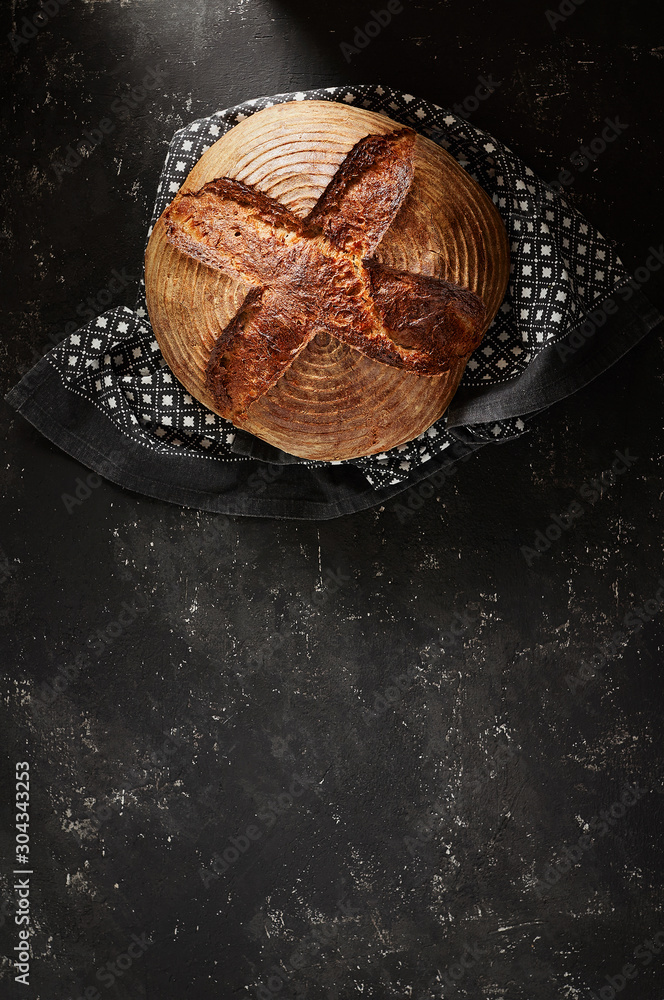 Freshly baked Artisan sourdough bread loaves with kitchen towel on black concrete backgroun