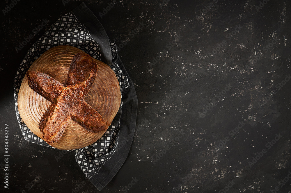 Freshly baked Artisan sourdough bread loaves with kitchen towel on black concrete backgroun
