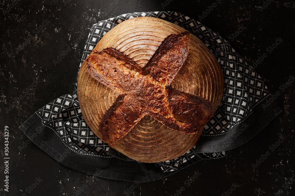 Freshly baked Artisan sourdough bread loaves with kitchen towel on black concrete backgroun