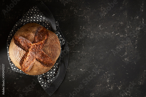 Obraz na płótnie Freshly baked Artisan sourdough bread loaves with kitchen towel on black concrete backgroun w salonie