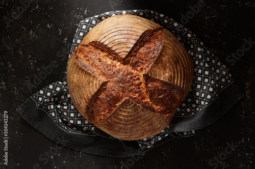 Obraz na płótnie Freshly baked Artisan sourdough bread loaves with kitchen towel on black concrete backgroun w salonie