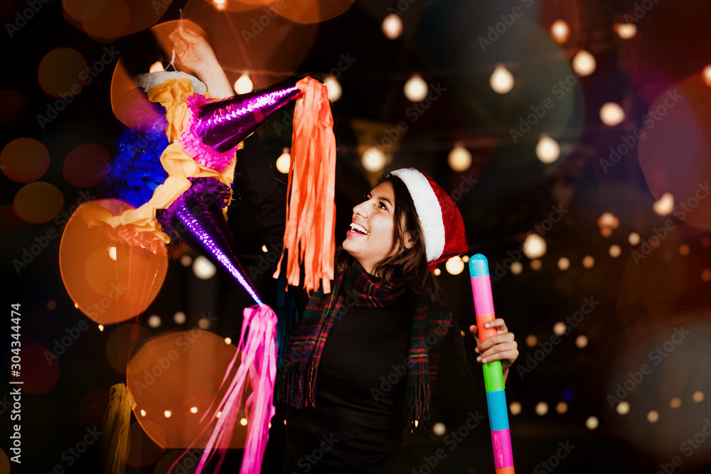 Mexican Christmas, Hispanic Woman Holding a colorful Piñata and celebrating a traditional Posada in Mexico
