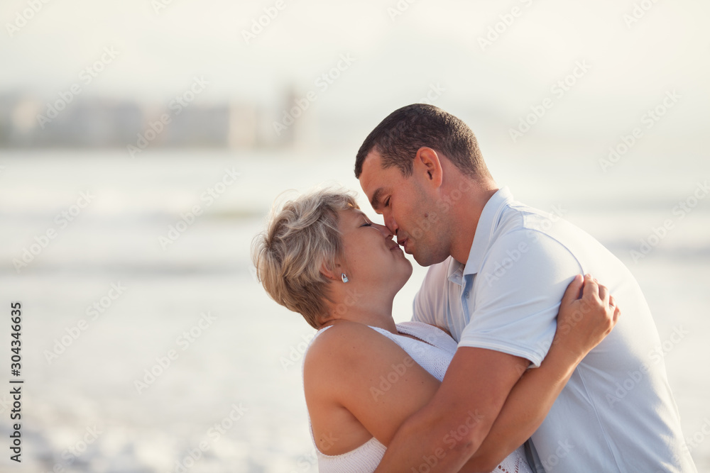 Portrait of a happy lovers husband and wife. Couple walks along the sea at sunrise Portrait of a happy lovers husband and wife. Couple walks along the sea at sunrise