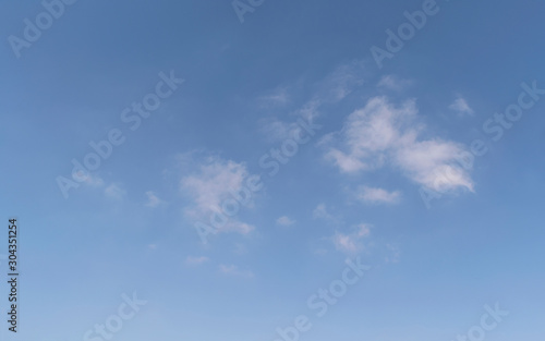 abstract cloudscape of small wispy puffy clouds in a clear blue sky with a little haze at the bottom