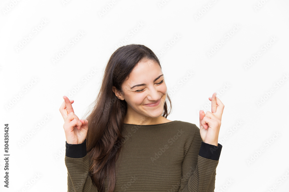 Excited happy Latin woman keeping fingers crossed. Young woman in casual standing isolated over white background. Making wish concept Excited happy Latin woman keeping fingers crossed. Young woman in casual standing isolated over white background. Making wish concept