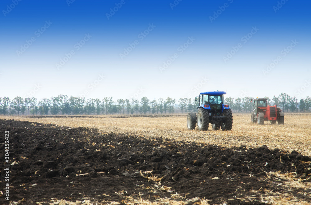 Fototapeta premium Modern tractors in the field during planting. The concept of agricultural industry.