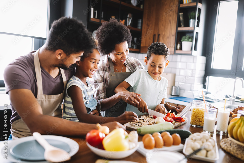 Plakat Happy african american family preparing healthy food together in kitchen