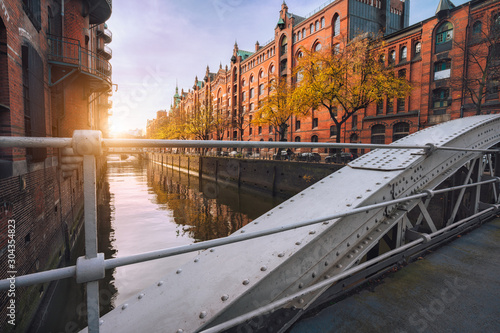 Arch bridge over canals in the Speicherstadt of Hamburg, Germany, Europe. Historical red brick building lit by warm soft golden sunset light