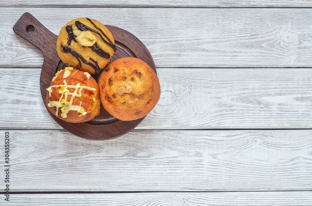 Sweet and tasty snack. Three different colorful cupcakes on a wooden background. Sweet and tasty snack. Three different colorful cupcakes on a wooden background.