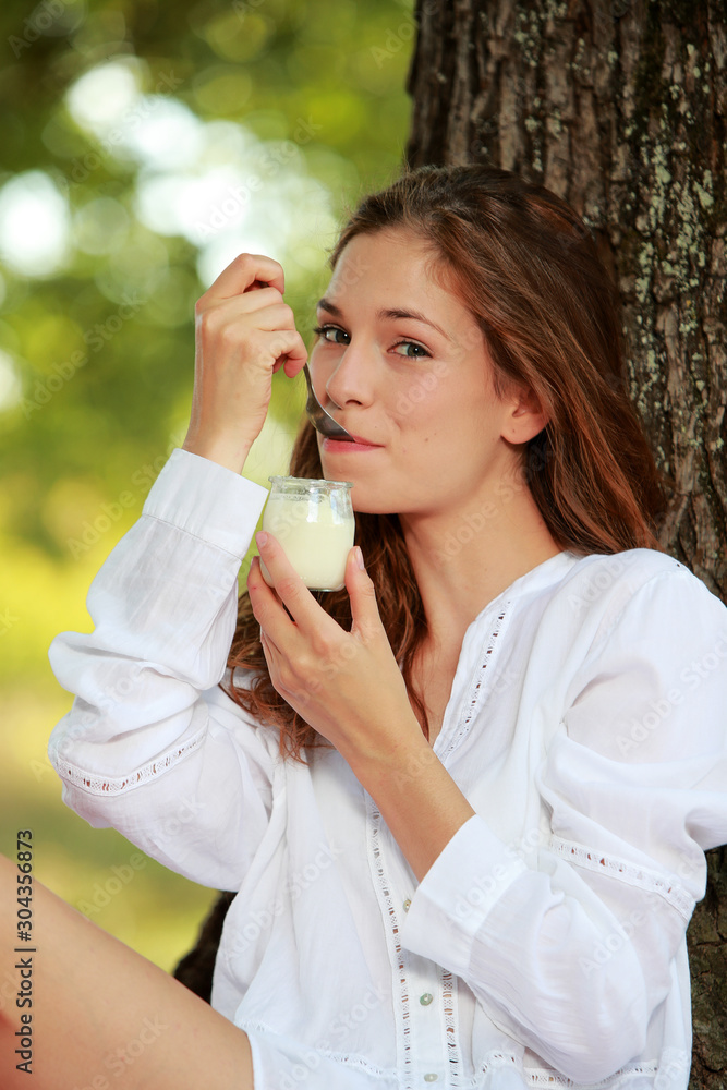 Jolie jeune femme assise mangeant un Yahourt