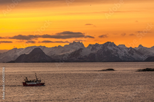 fishing boat with amazing sunset in background in lofoten, norway.