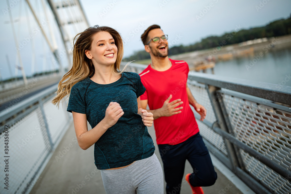 Obraz premium Early morning workout. Happy couple running across the bridge