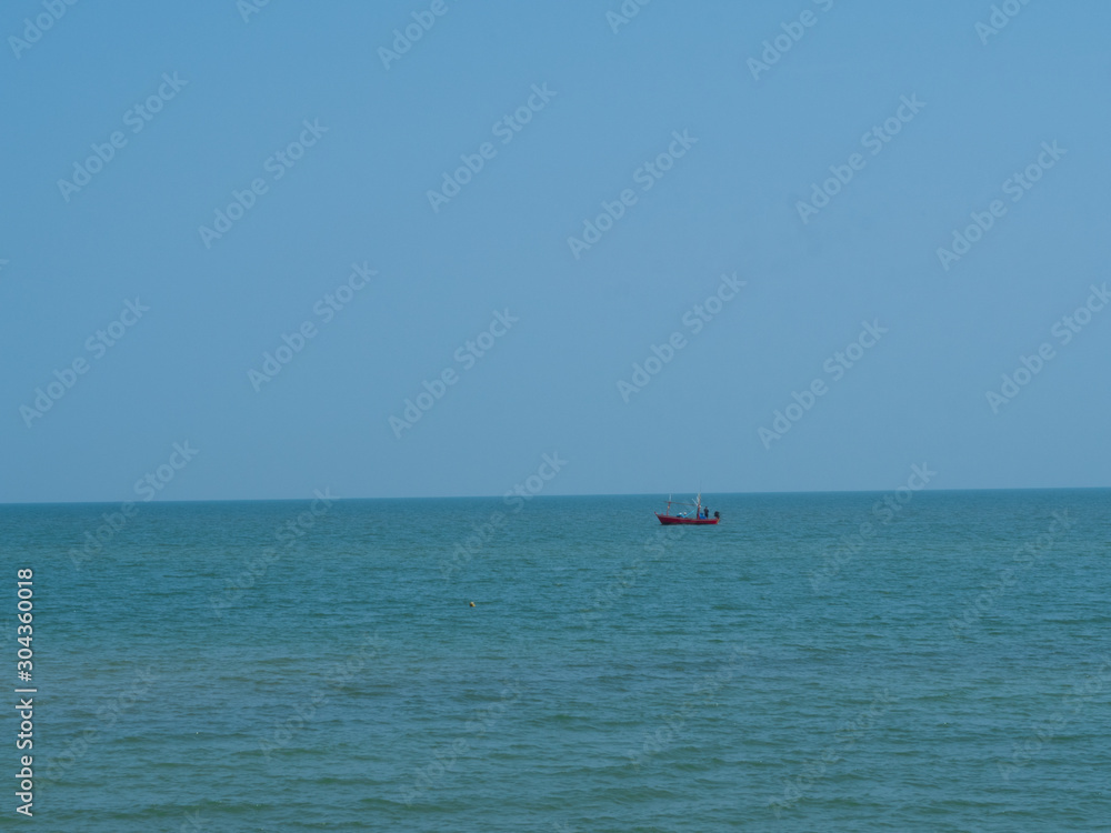 Blue sea with a boat and blue sky at Cha am - Thailand