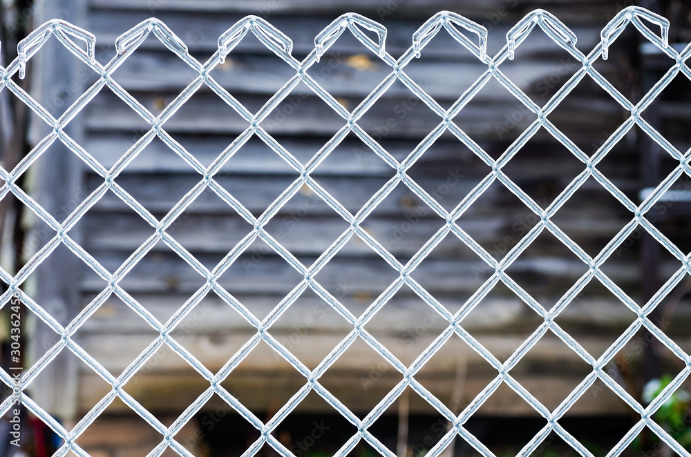 Fototapeta premium Ice on a fence made of metal mesh. Icy rain in the winter. Atmospheric phenomena of nature.