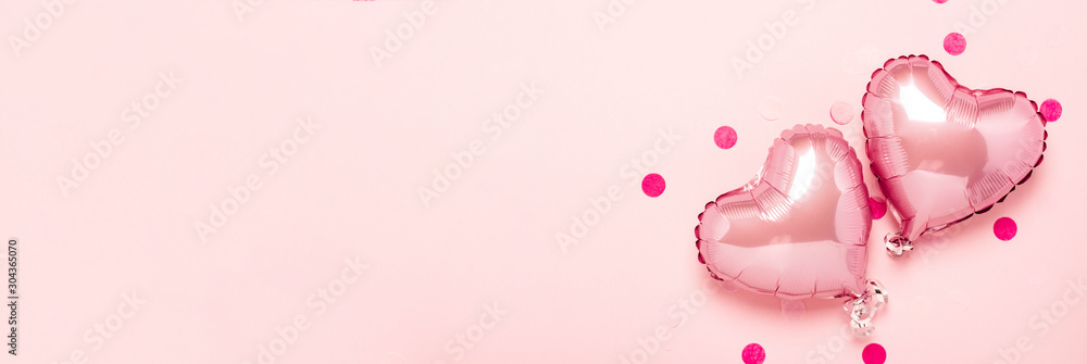 Two pink air balloons in the shape of a heart on a pink background. Concept Valentine's Day, Wedding Decoration. Foil balls. Banner. Flat lay, top view