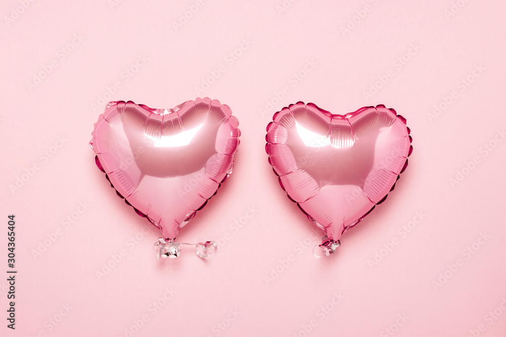Two pink air balloons in the shape of a heart on a pink background. Concept Valentine's Day, Wedding Decoration. Foil balls. Flat lay, top view