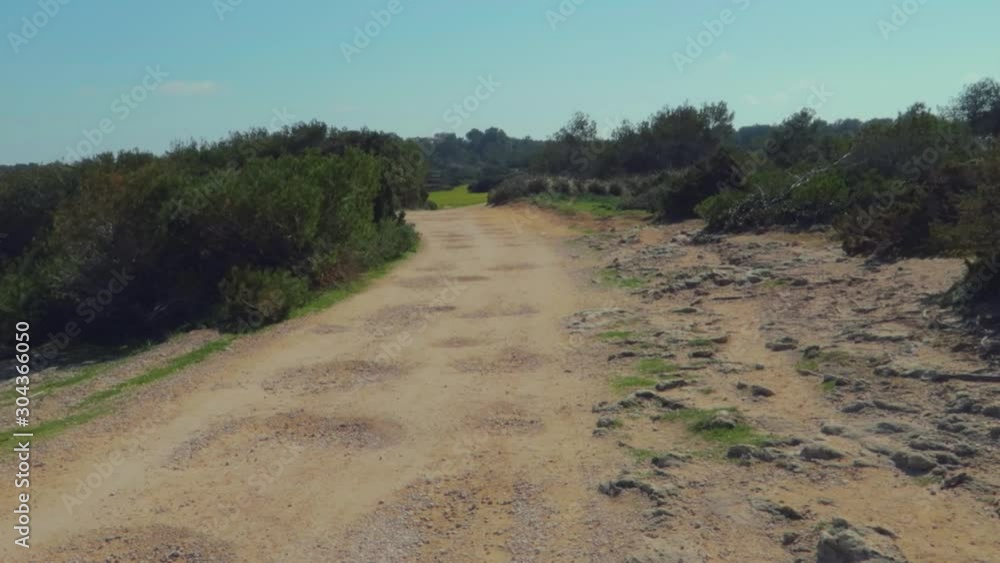 A gravel road surrounded with forest going to cala millor near mountains. mallorca, spain, A hand held slow mo view. A gravel road surrounded with forest going to cala millor near mountains. mallorca, spain, A hand held slow mo view.
