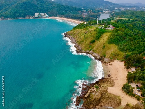 Wind turbine Panorama drone aerial view electricity windmill overlooking Naiharn beach phuket Thailand turquoise blue waters white golden sandy beach lush green mountains © Elias Bitar