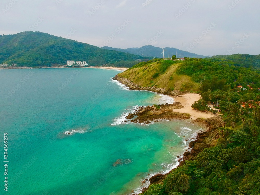 Wind turbine  Panorama drone aerial view electricity windmill overlooking Naiharn beach phuket Thailand turquoise blue waters white golden sandy beach lush green mountains 