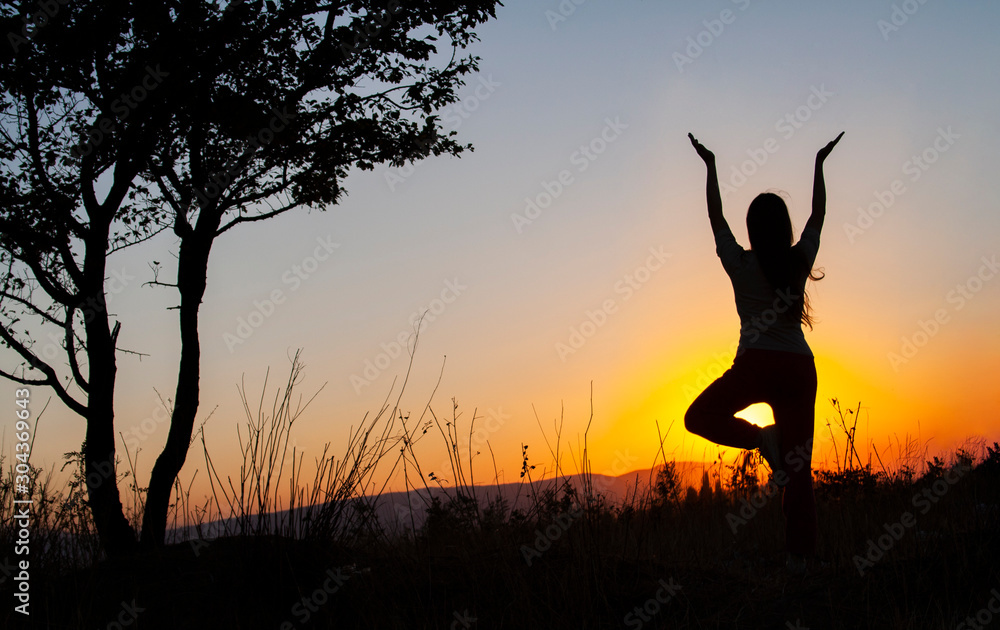 Yoga tree pose by woman silhouette with sunset. Virabhadrasana, Hatha